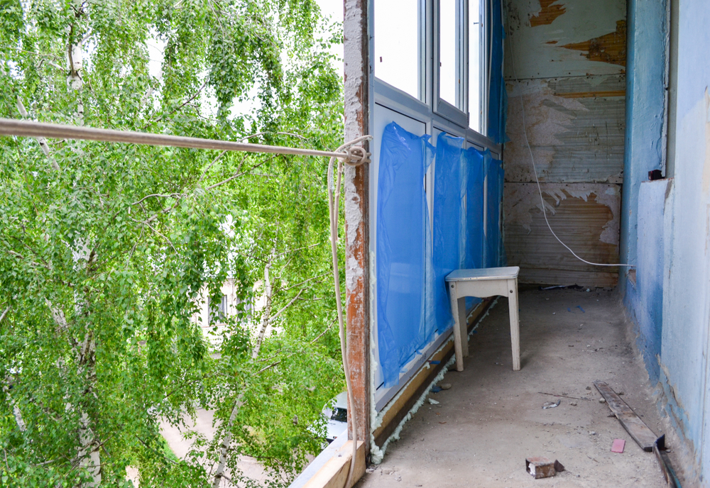 un balcon in proces de renovare cu pereti daramati sapa expusa si termopane nou montate