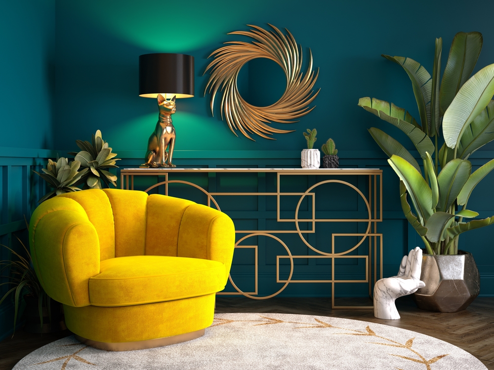 Amenajare cu mobilier art deco, fotoliu galben din catifea, comodă neagră cu linii geotrice aurii, oglindă circulară cu ramă aurie pe fundal cu perete de accent verde smarlad închis.