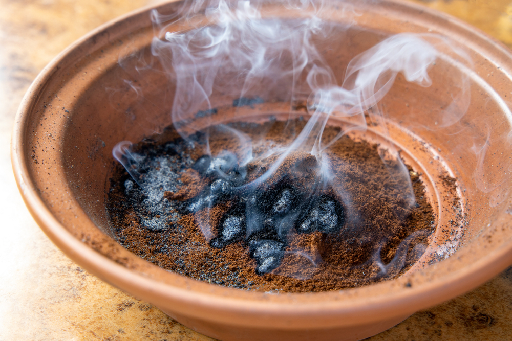 Un vas de teracota cu cafea măcinată fumegând ca soluție tânțari exterior.