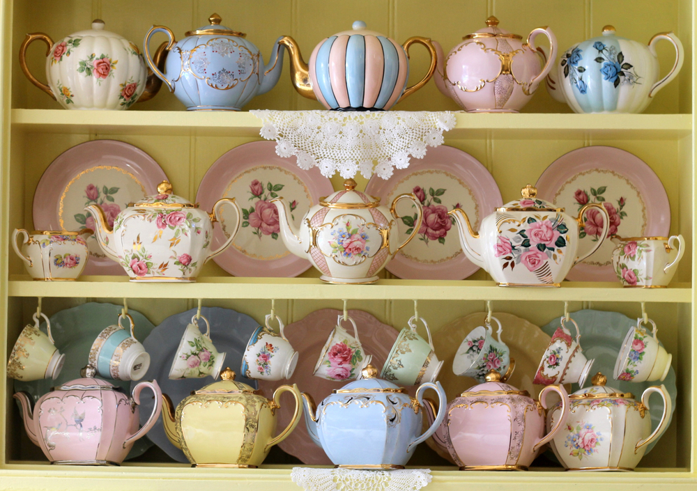 O vitrină cu veselă din porțelan vintage în nuanțe pastelate și cu imprimeuri florale.
