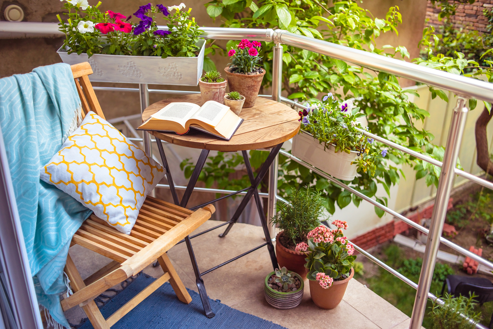 balcon mic amenajat ca spatiu de relaxare cu scaun, masa si flori