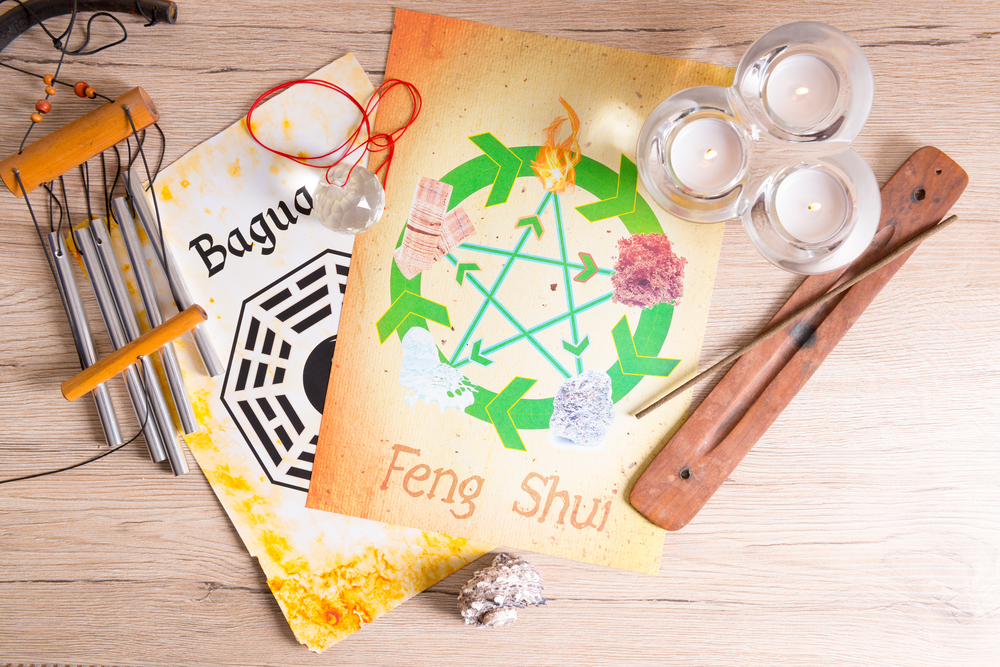 Imagine conceptuală Feng Shuii cui hartă bagua, cele cinci elemente, bilă de cristal, lumânări pastilă albe și bețișor parfumat în suport de lemn