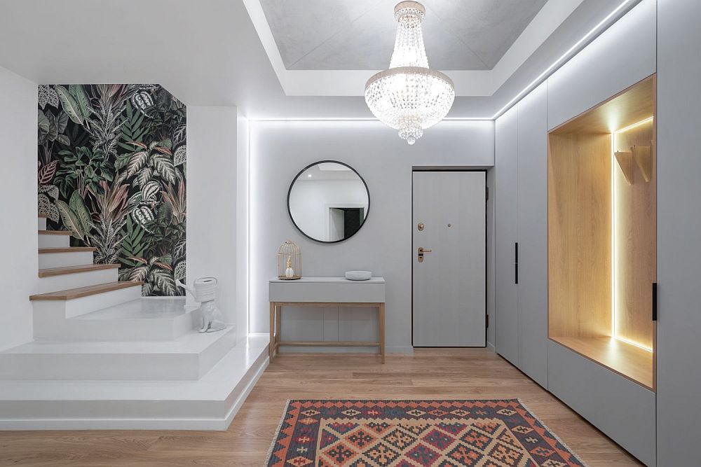 Parchet sau gresie pe hol - un hol modern cu parchet din lemn natur, pereți albi, candelabru și covor cu modele geometrice.
