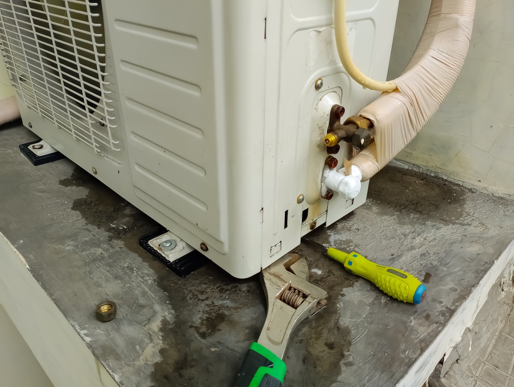 Unitate exterioară de AC cu scurgeri de apă și unelte pentru reparare.