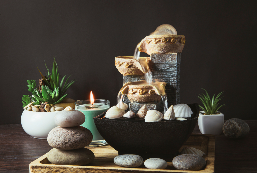 O fântână feng shui cu pietre și plante și lumânare pe un fundal negru