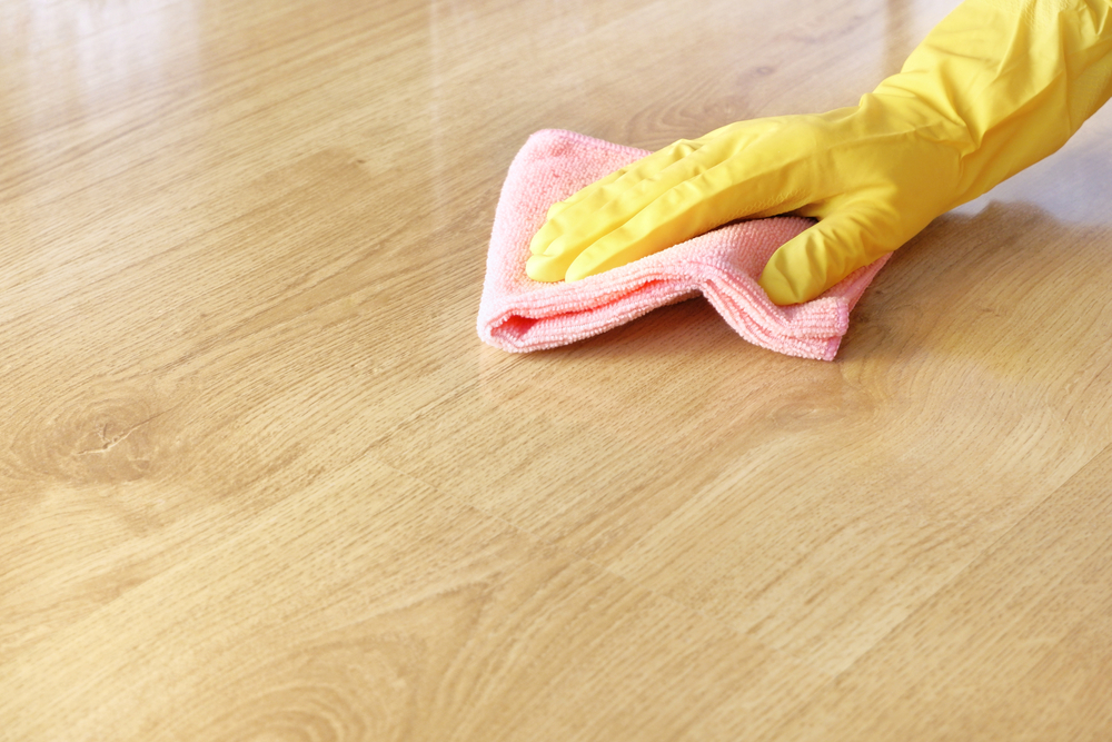 curatare parchet laminat cu carpa microfibre de catre persoana cu manusa galbena