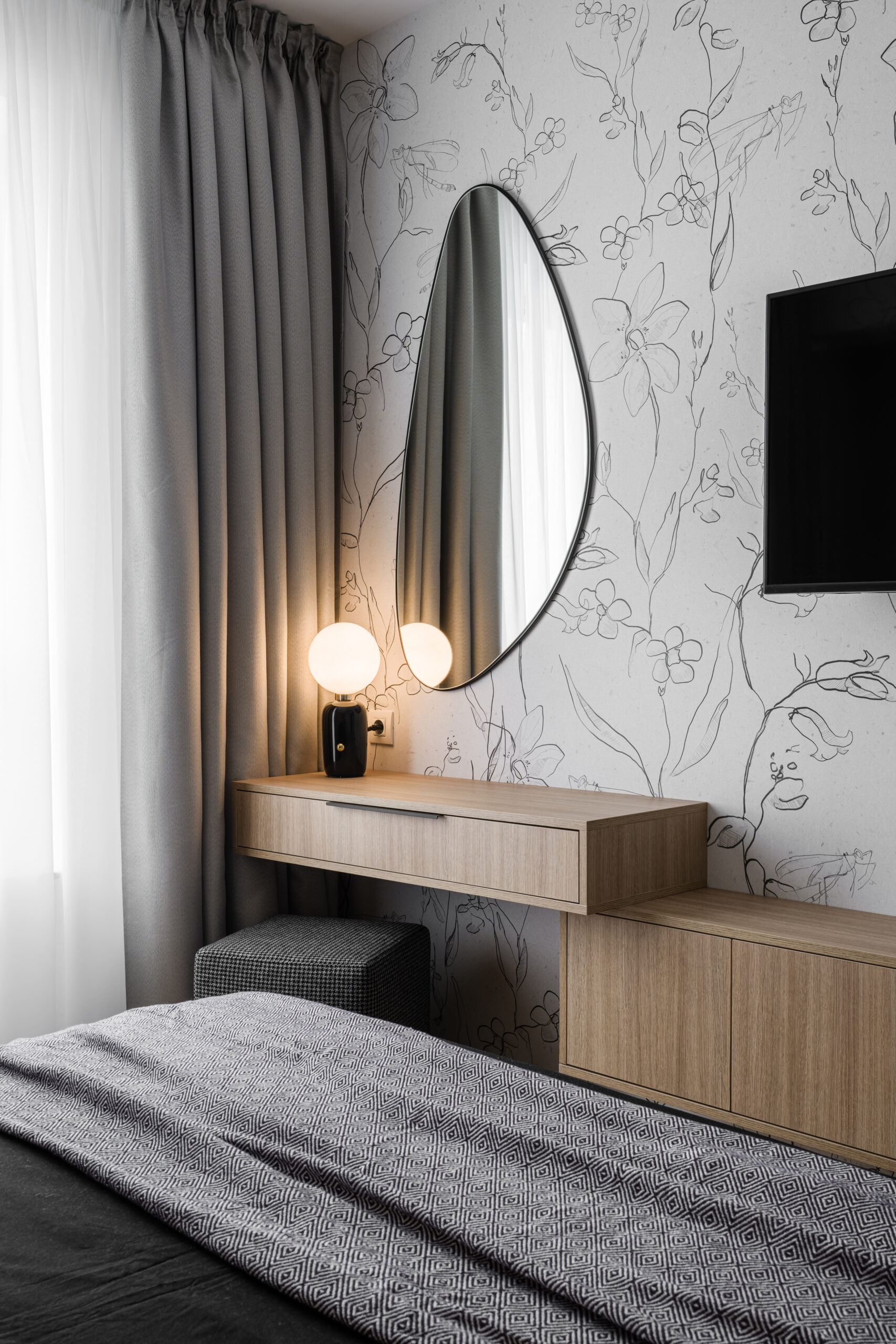 zona cu masuta de machiaj in dormitor perete cu tapet model floral mobilier mdf cu finisaj lemn natur accesorii textile gri