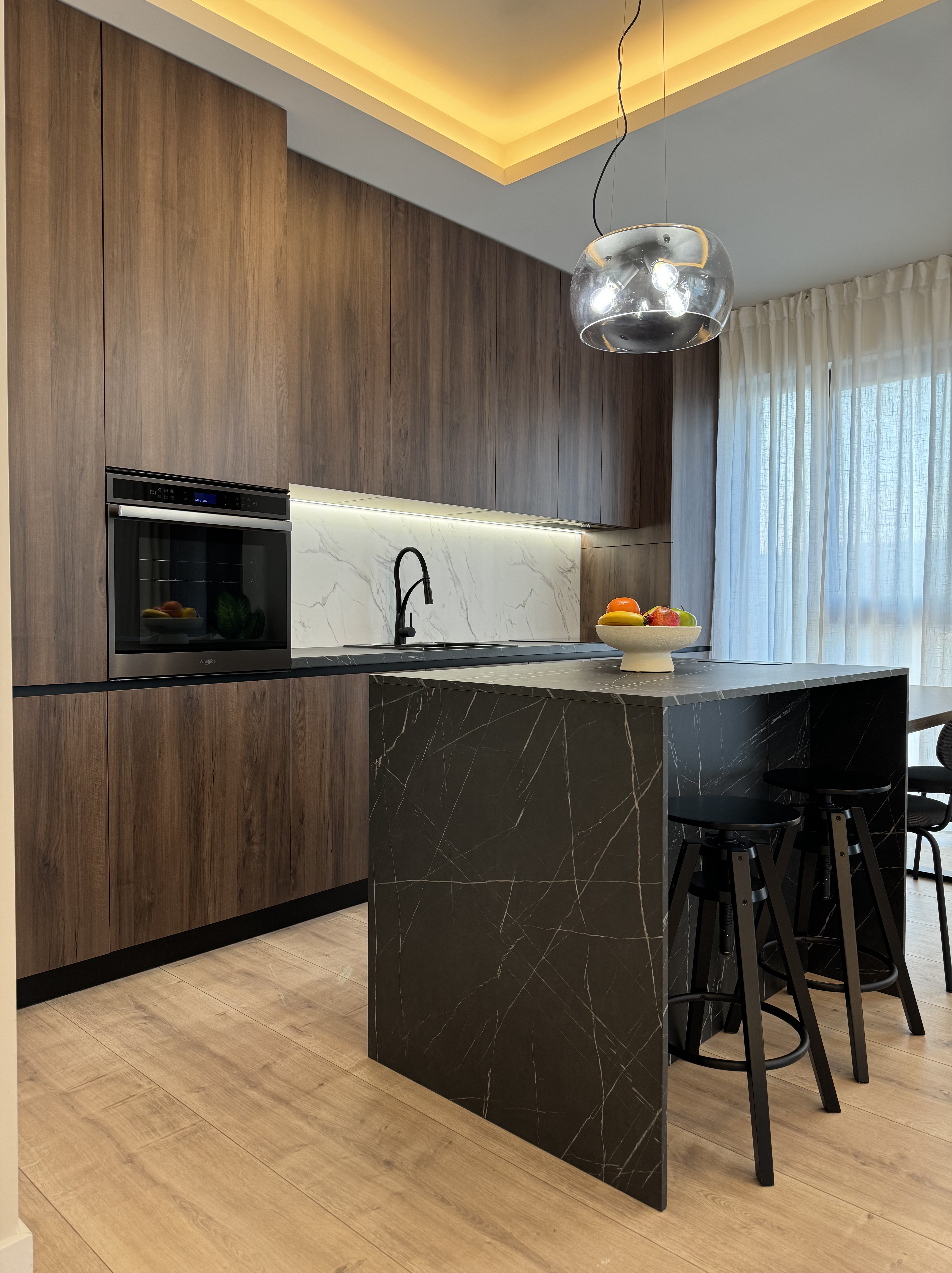 Bucatarie amenajata cu fronturi lemn de nuc si insula imitatie marmura parchet laminat